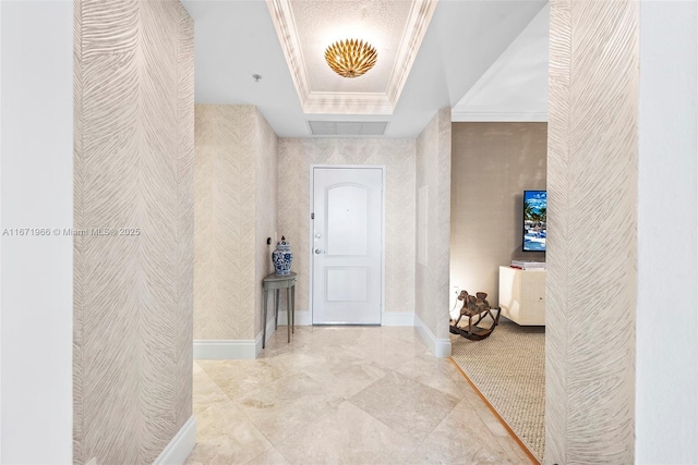 entryway featuring a raised ceiling and crown molding