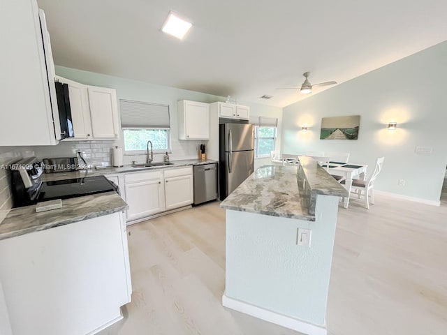 kitchen featuring decorative backsplash, white cabinets, a healthy amount of sunlight, and stainless steel appliances