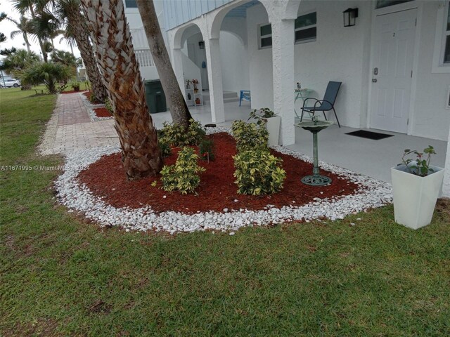 entrance to property featuring a patio and a lawn