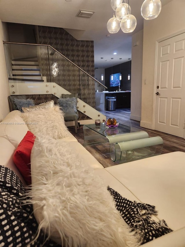 living room with stairway, visible vents, and wood finished floors