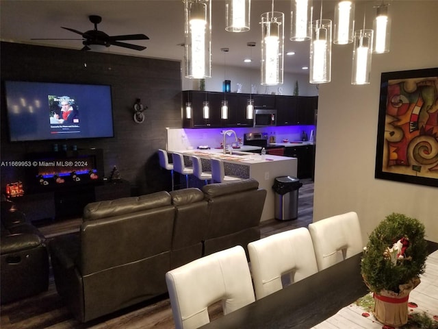 cinema room featuring wood-type flooring, wooden walls, sink, and ceiling fan