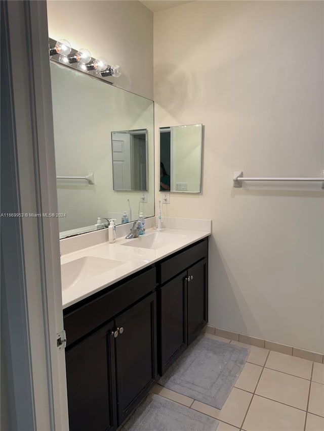 bathroom featuring tile patterned floors, double vanity, a sink, and baseboards