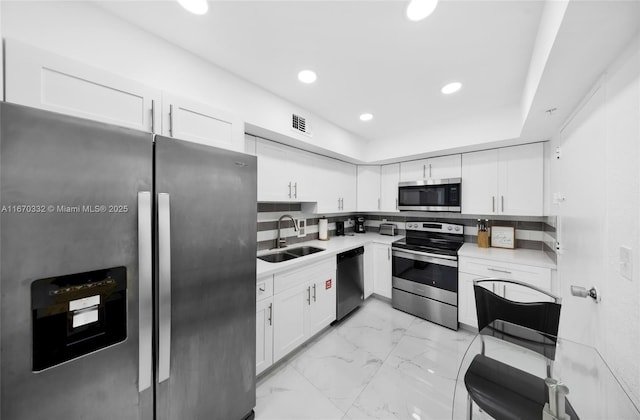 kitchen with marble finish floor, stainless steel appliances, visible vents, white cabinetry, and a sink