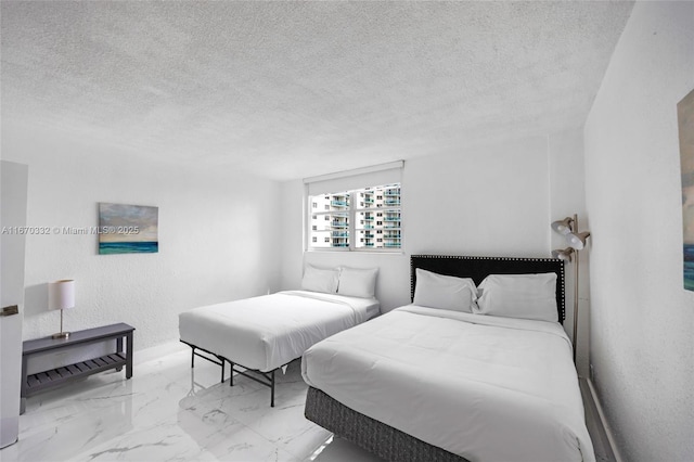 bedroom featuring marble finish floor, a textured wall, and a textured ceiling