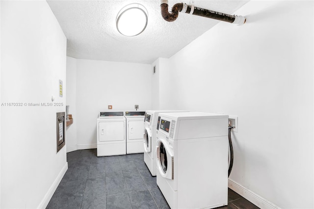 community laundry room with a textured ceiling, dark tile patterned flooring, washing machine and dryer, and baseboards