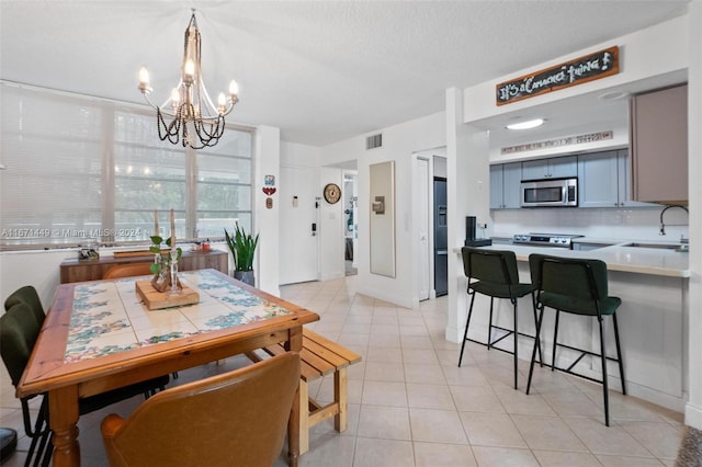 tiled dining area featuring a textured ceiling, sink, and a chandelier