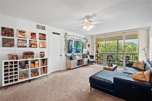 living room with carpet, ceiling fan, expansive windows, and a textured ceiling