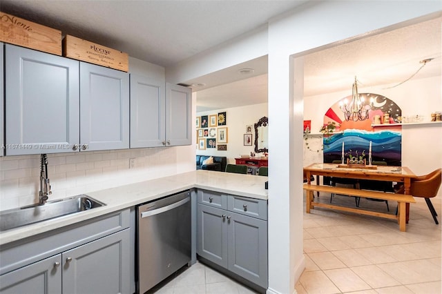 kitchen with backsplash, stainless steel dishwasher, gray cabinetry, sink, and an inviting chandelier