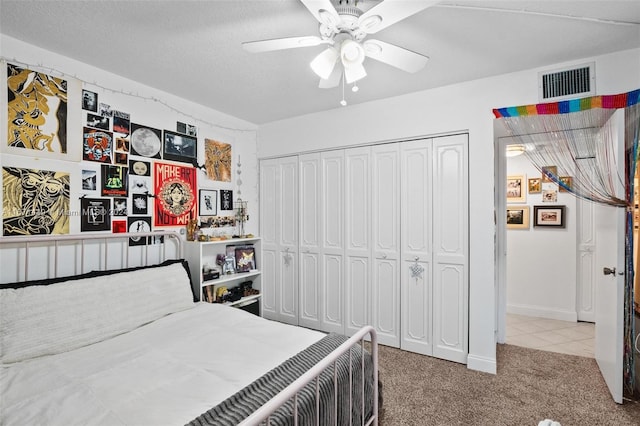 carpeted bedroom with ceiling fan, a closet, and a textured ceiling