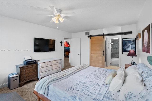 carpeted bedroom featuring ensuite bathroom, ceiling fan, a barn door, and a closet