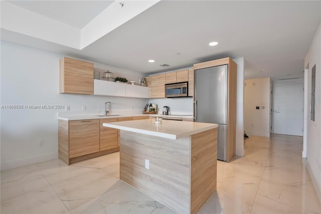 kitchen featuring light brown cabinetry, appliances with stainless steel finishes, sink, and a kitchen island