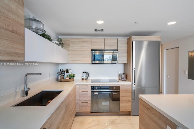 kitchen with light brown cabinetry, appliances with stainless steel finishes, and sink