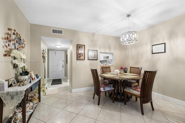 tiled dining space featuring a textured ceiling and an inviting chandelier