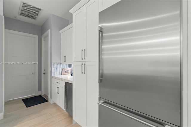 kitchen featuring built in fridge, light wood-type flooring, and white cabinets