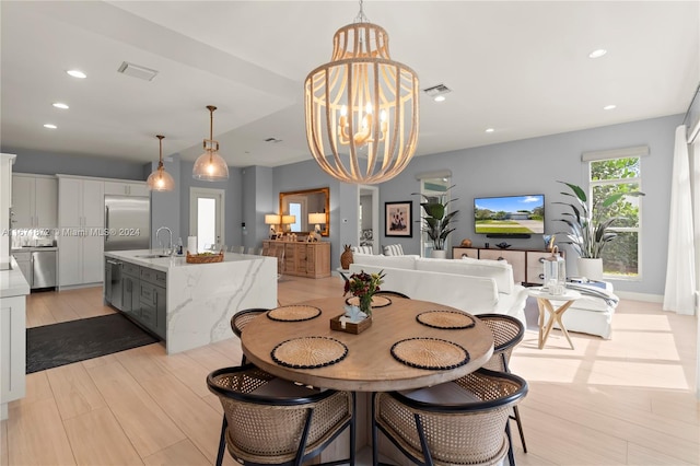 dining room with a chandelier, sink, and light wood-type flooring