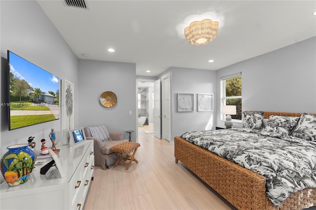 bedroom with connected bathroom and light hardwood / wood-style floors