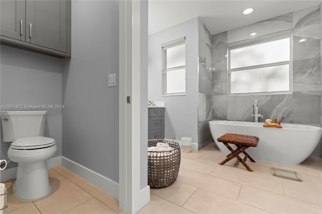 bathroom featuring vanity, a tub, tile patterned flooring, and toilet