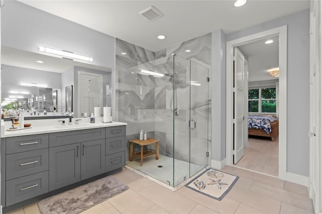 bathroom featuring a shower with shower door, vanity, and tile patterned floors