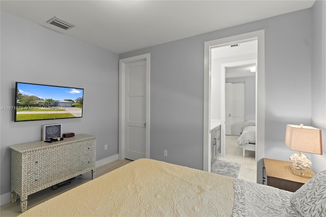 bedroom with ensuite bath and light wood-type flooring