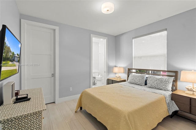 bedroom with connected bathroom and light wood-type flooring