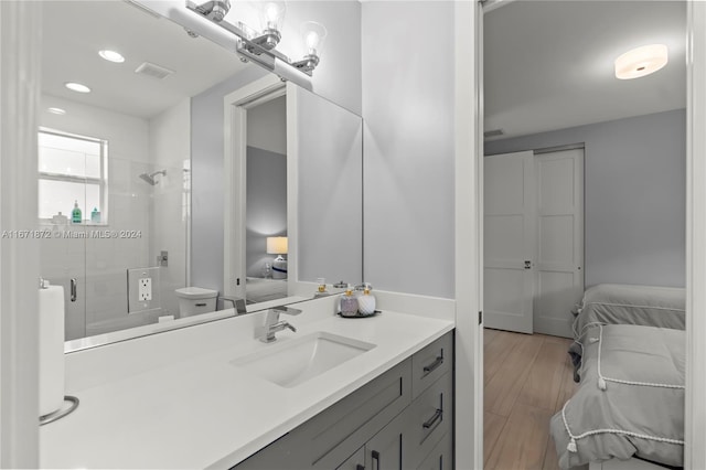 bathroom featuring toilet, vanity, hardwood / wood-style flooring, and a shower with shower door