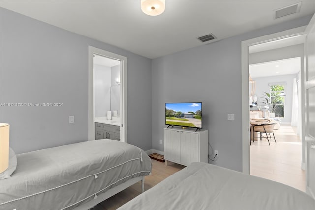 bedroom with ensuite bathroom and light hardwood / wood-style floors