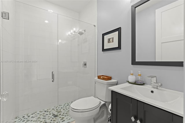 bathroom featuring a shower with shower door, vanity, and toilet