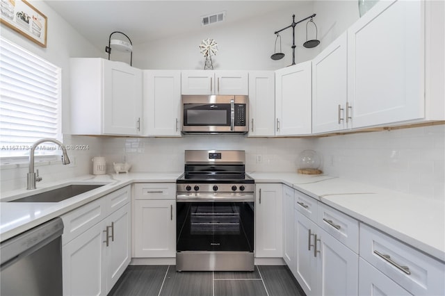 kitchen featuring stainless steel appliances, sink, tasteful backsplash, lofted ceiling, and white cabinets