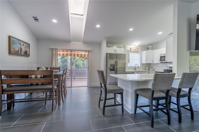 kitchen with white cabinetry, sink, a kitchen breakfast bar, and stainless steel appliances