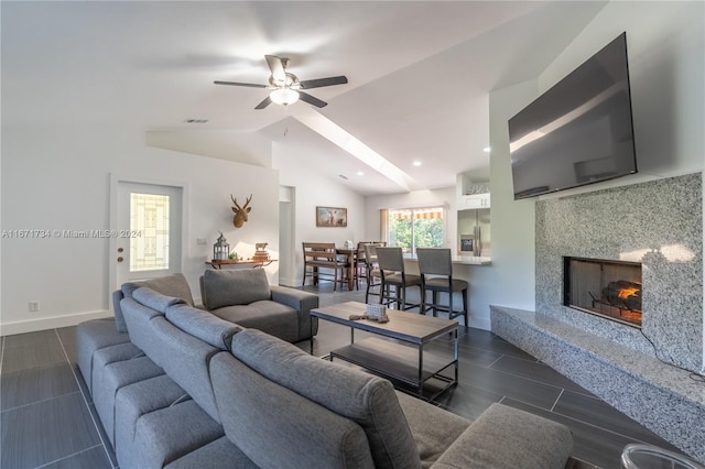 living room with a high end fireplace, ceiling fan, and vaulted ceiling