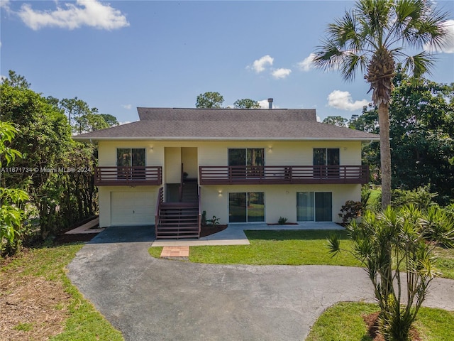 view of front of home featuring a garage, a front lawn, and a balcony