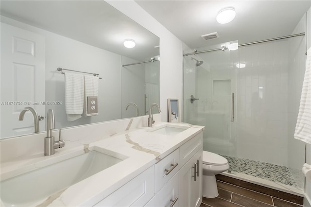 bathroom featuring a shower with door, vanity, and toilet