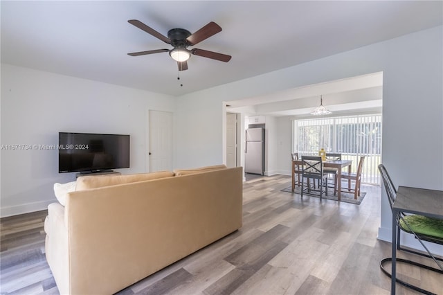 living room with hardwood / wood-style flooring and ceiling fan with notable chandelier