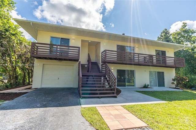 view of front of home featuring a balcony, a front yard, and a garage