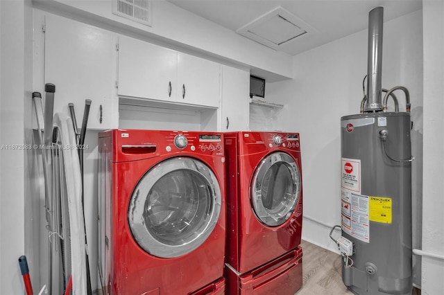 laundry area featuring light hardwood / wood-style floors, washer and clothes dryer, gas water heater, and cabinets