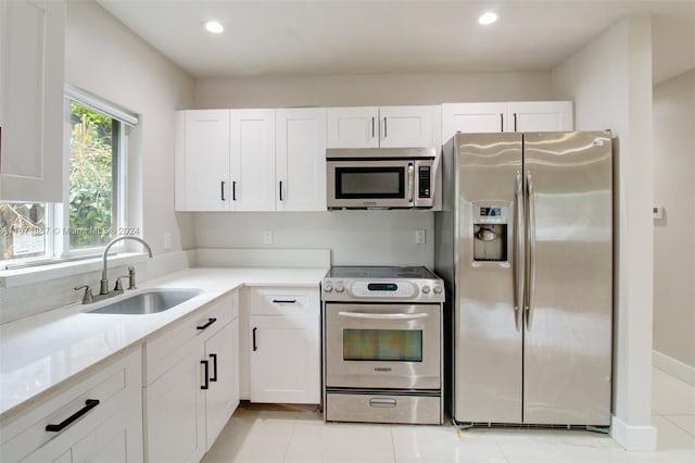 kitchen with stainless steel appliances, white cabinetry, light tile patterned floors, and sink