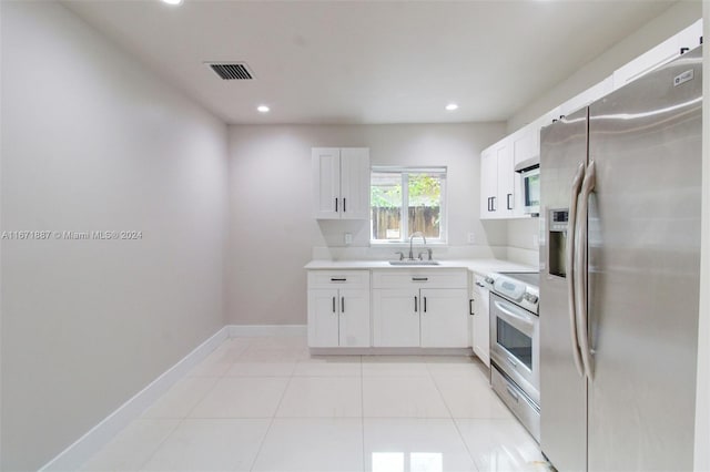 kitchen with stainless steel appliances, white cabinetry, light tile patterned floors, and sink