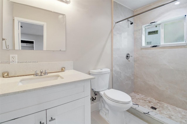 bathroom featuring tiled shower, vanity, and toilet