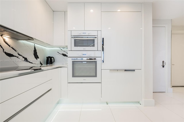 kitchen with white cabinetry, double oven, light tile patterned floors, and backsplash