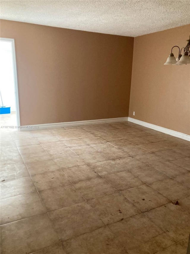 spare room with a textured ceiling and a notable chandelier