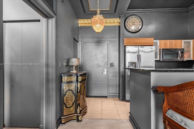 kitchen featuring appliances with stainless steel finishes, hanging light fixtures, light tile patterned floors, and dark stone counters