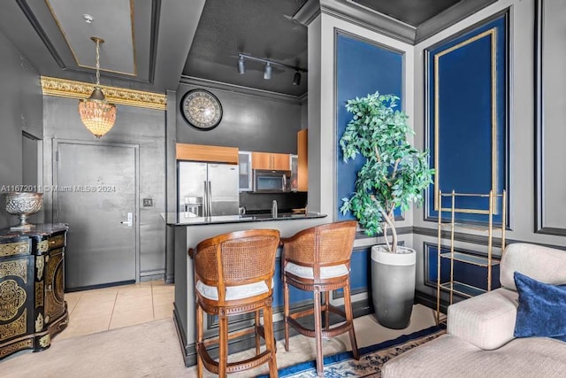 kitchen featuring pendant lighting, kitchen peninsula, track lighting, stainless steel appliances, and a kitchen bar