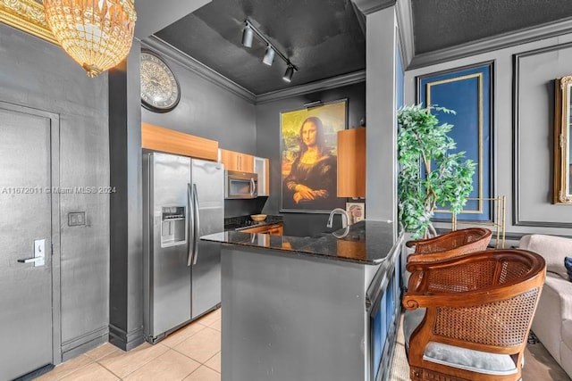 kitchen with appliances with stainless steel finishes, kitchen peninsula, light tile patterned floors, track lighting, and ornamental molding