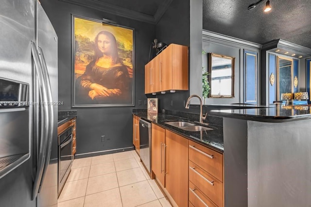 kitchen with a textured ceiling, sink, appliances with stainless steel finishes, ornamental molding, and dark stone countertops