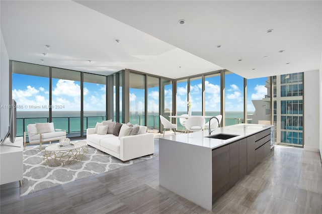 kitchen featuring a center island with sink, floor to ceiling windows, sink, and a water view