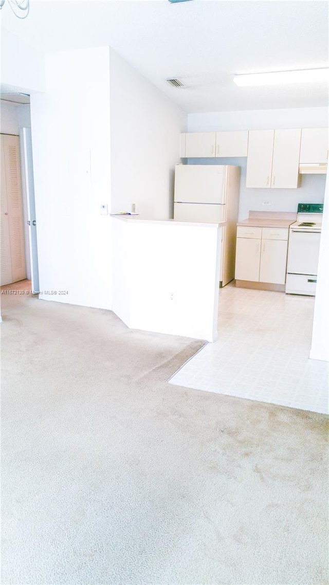 kitchen featuring white cabinets, light colored carpet, and white appliances