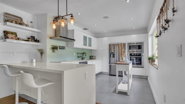 kitchen featuring hanging light fixtures, kitchen peninsula, stainless steel appliances, and white cabinets