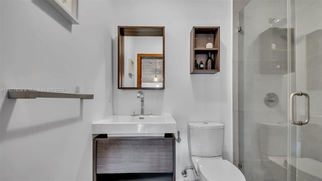 bathroom with a shower with door, vanity, and toilet