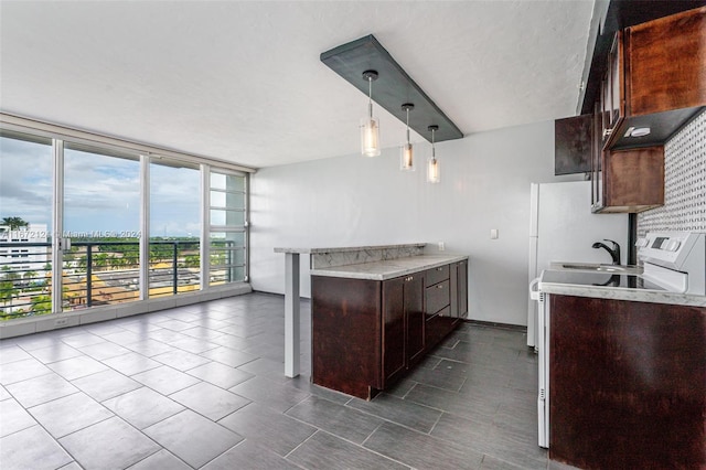 kitchen with dark brown cabinets, dark tile patterned flooring, a textured ceiling, sink, and hanging light fixtures