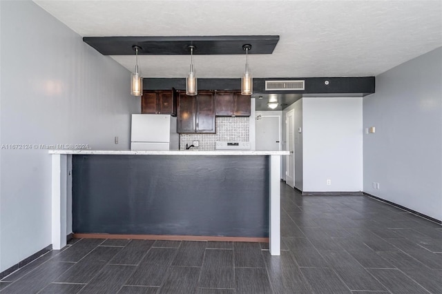 kitchen featuring decorative backsplash, pendant lighting, white fridge, a textured ceiling, and dark brown cabinets